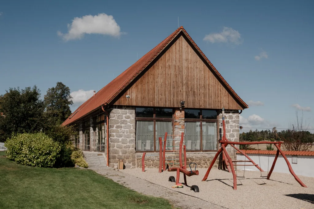Hlavní budova areálu Pohoda Nárameč s kamennou fasádou a dětským hřištěm v zahradě.
