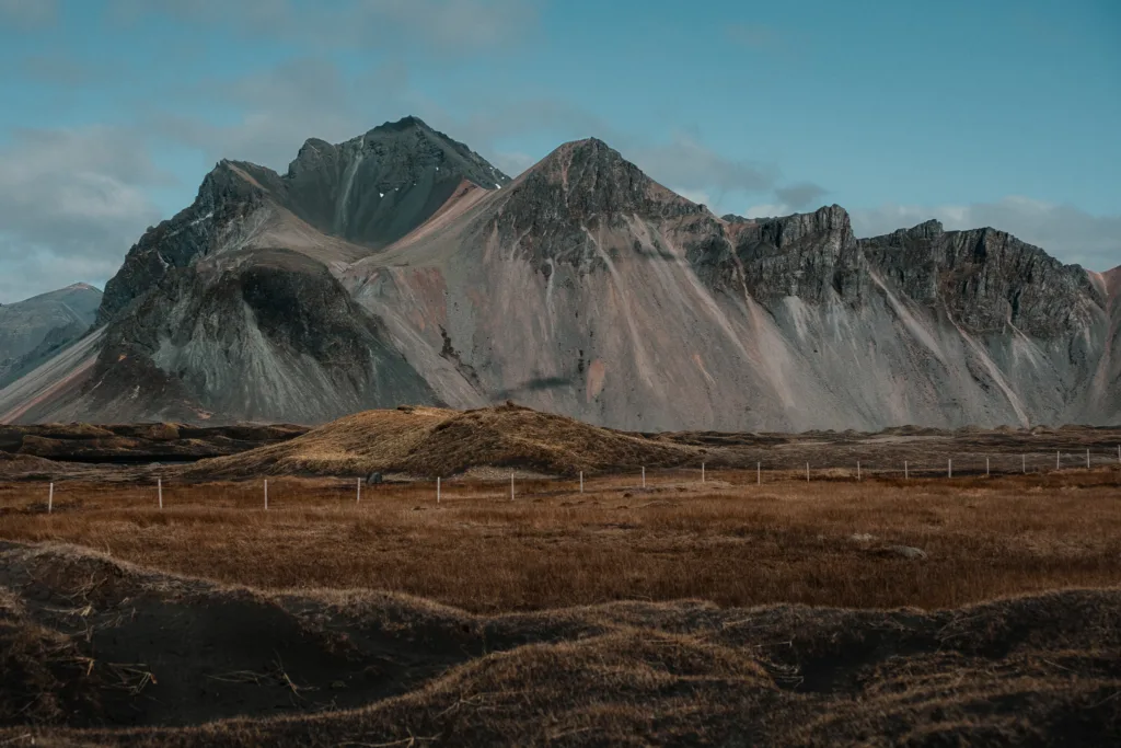 Minimalistická islandská krajina s barevně vrstvenými horskými svahy a tlumenými přírodními tóny.
